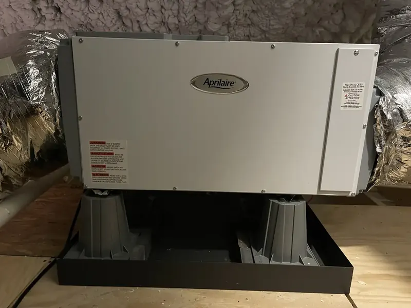 Aprilaire standalone whole-home dehumidifier installed on a stand in a Southern NH attic by A.J. LeBlanc Heating