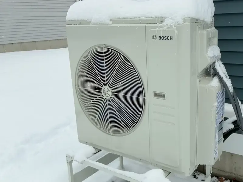 Bosch outdoor heat pump operating in winter with snow on the unit at a Southern NH home