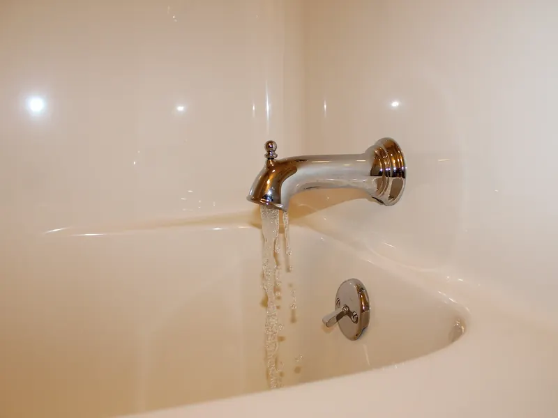 Chrome tub spout with water flowing into a bathtub during a final fixture check by A.J. LeBlanc Heating in a Southern NH home