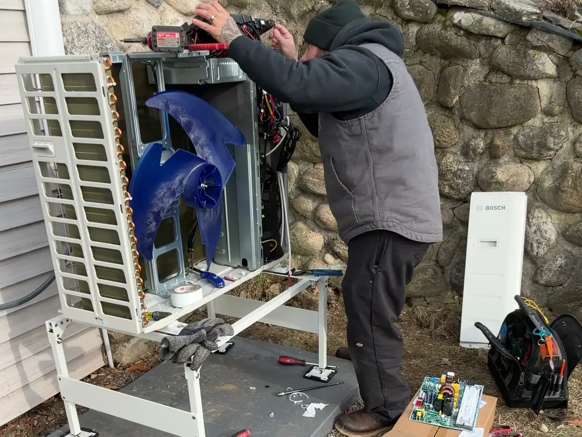 A.J. LeBlanc Heating technician opening a ductless mini split heat pump outdoor unit for component-level service and control board replacement in Southern NH
