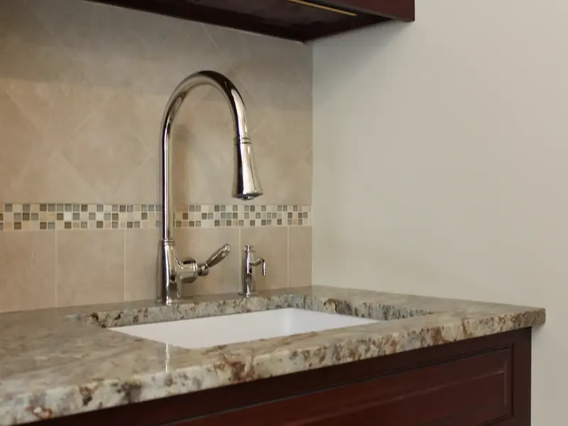 Chrome pull-down kitchen faucet with glass mosaic backsplash installed by A.J. LeBlanc Heating in a Southern NH home