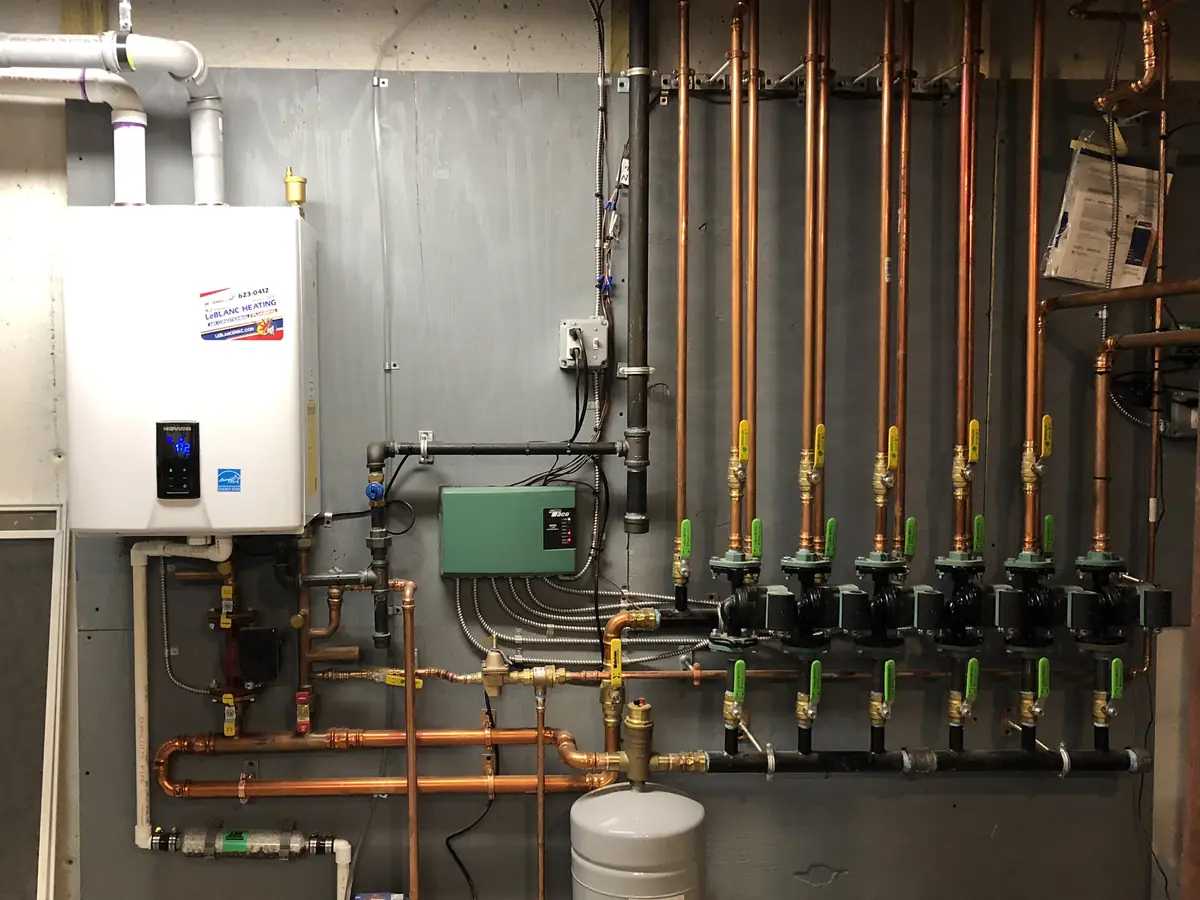 Navien wall-hung condensing boiler with multi-zone copper hydronic manifold and Taco circulators in a Southern NH basement