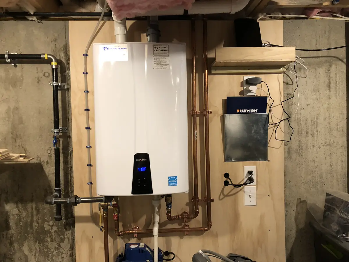 A.J. LeBlanc Heating Navien tankless water heater installation with copper plumbing and gas line on plywood backing in a Southern NH basement