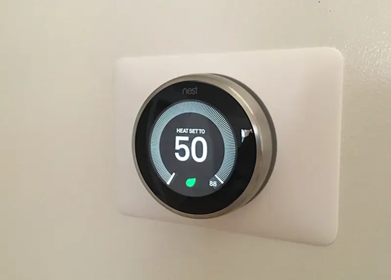 Google Nest smart thermostat with mounting plate installed by A.J. LeBlanc Heating in a Southern NH home