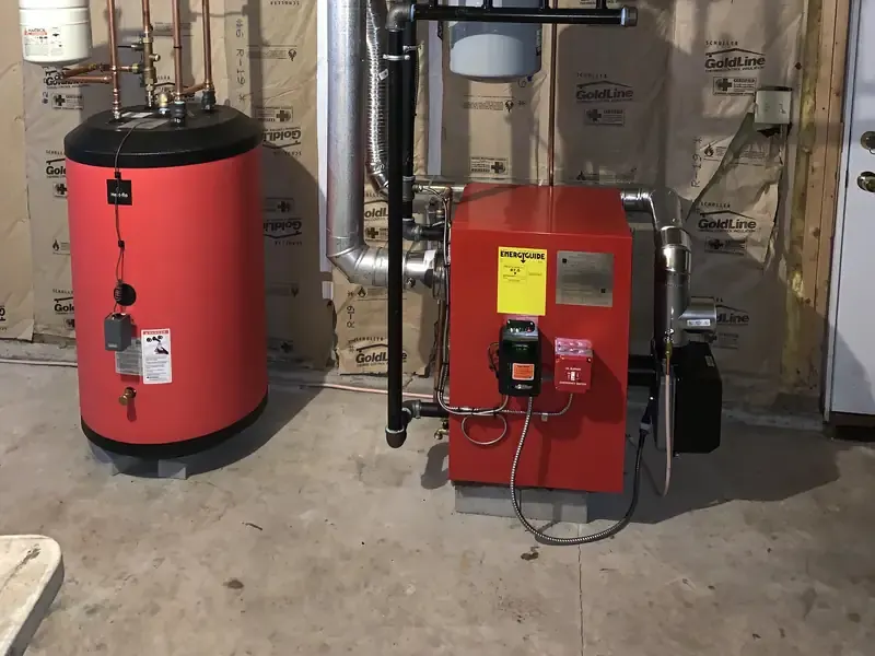 Red oil boiler with Beckett burner and matching red indirect water heater installed in a Southern NH basement