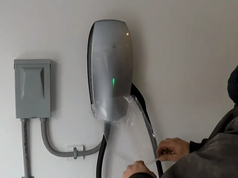 A.J. LeBlanc Heating electrician installing a Tesla Wall Connector in a Southern NH garage