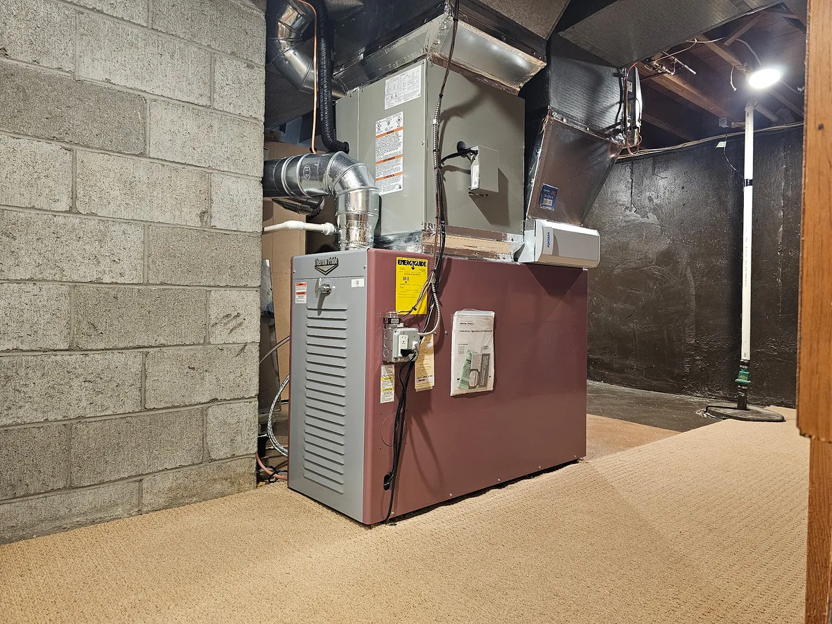 Thermo Pride oil furnace with insulated supply plenum and ductwork serviced by A.J. LeBlanc Heating in a Southern NH cinder-block basement