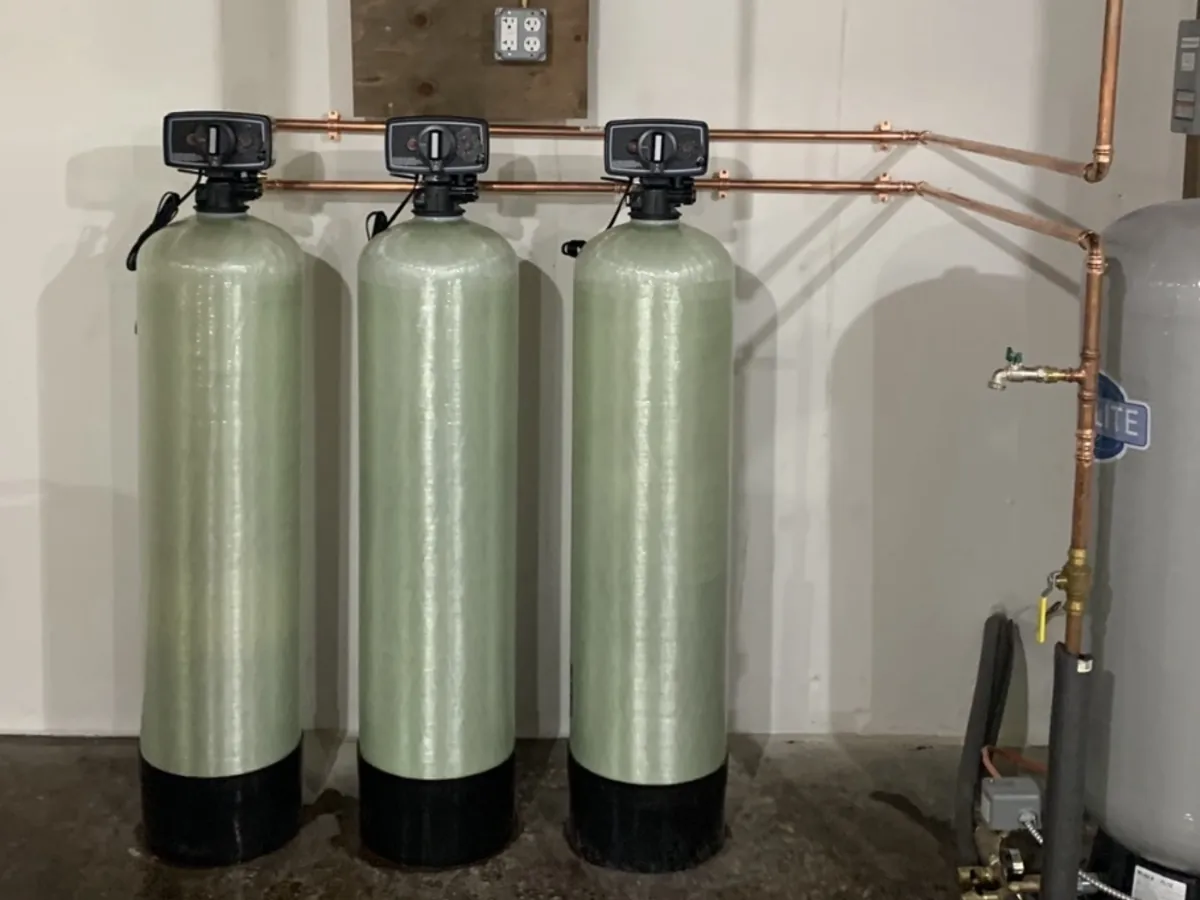 Three-tank well water filtration system with copper plumbing and manual control valves installed by A.J. LeBlanc Heating in a Southern NH basement
