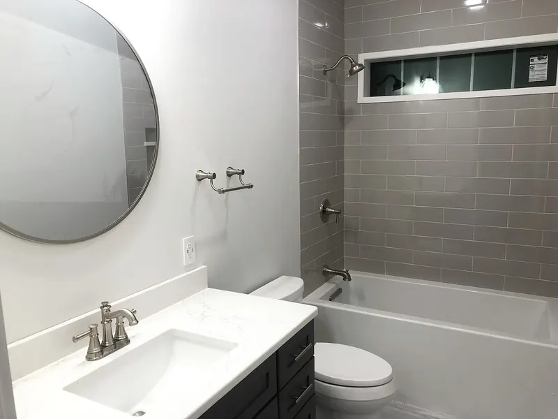 Tub and shower combo with gray subway tile surround, brushed nickel fixtures, and a recessed niche installed by A.J. LeBlanc Heating in a Southern NH bathroom